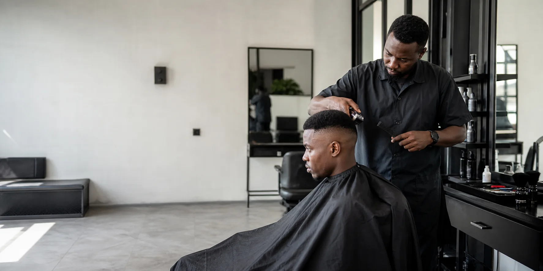 A barber shaping a precision haircut inside the studio